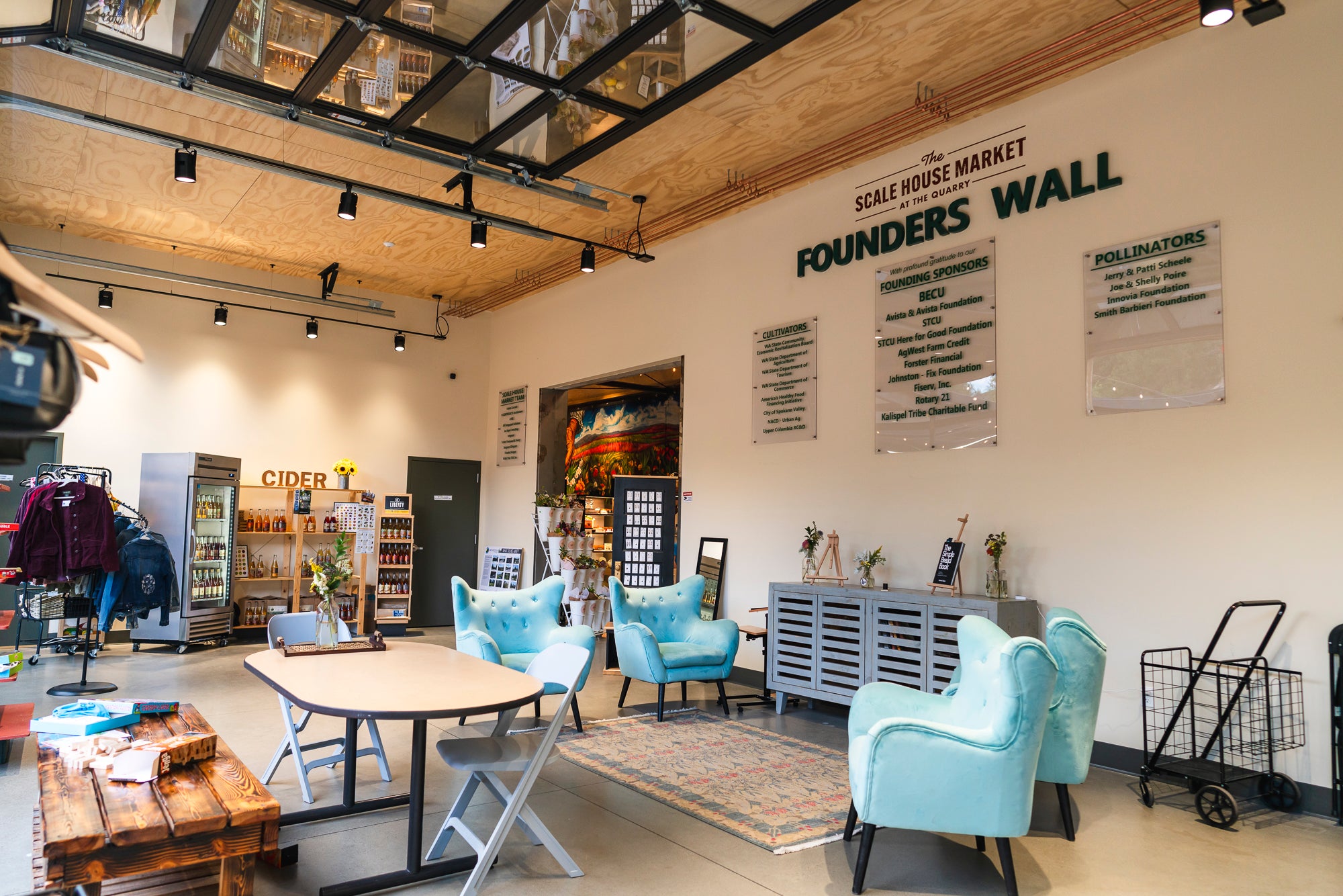 Modern interior with blue chairs, wooden tables, and 'Founders Wall' on the wall.